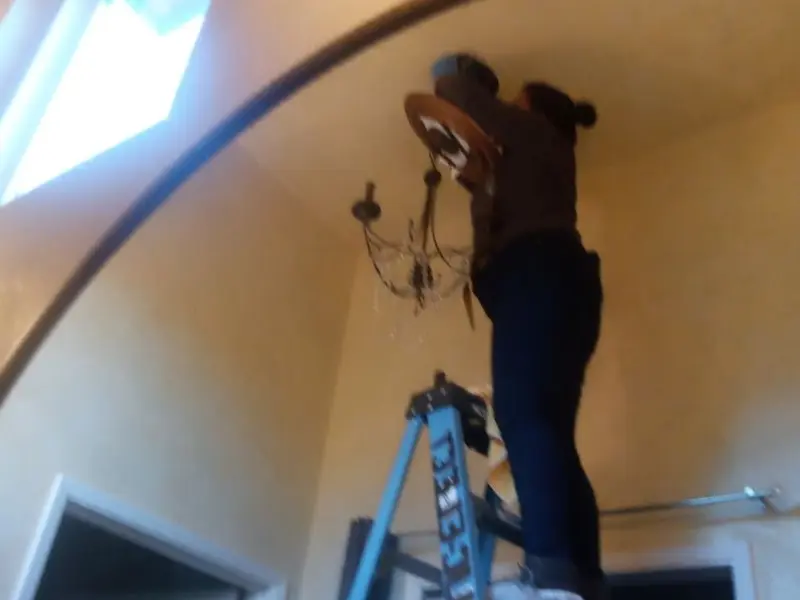 Electrician installing a chandelier in a Seven Oaks residence